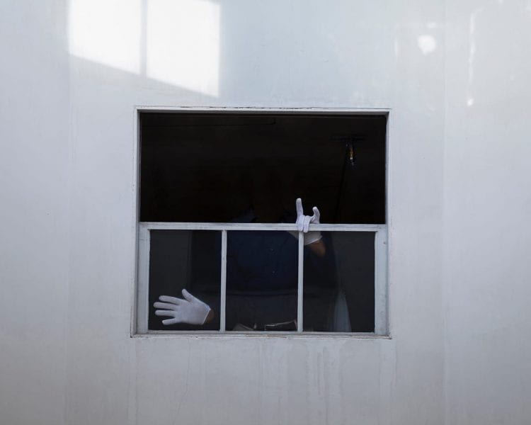 View of a window from outside. We see only the white-gloved hands of someone inside.